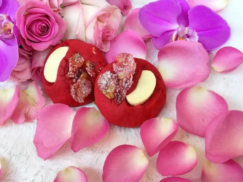 Mise en scène artistique de cookies rouges à la rose sur fond de fourrure blanche, orchidées et pétales de roses, Cindy Gunther