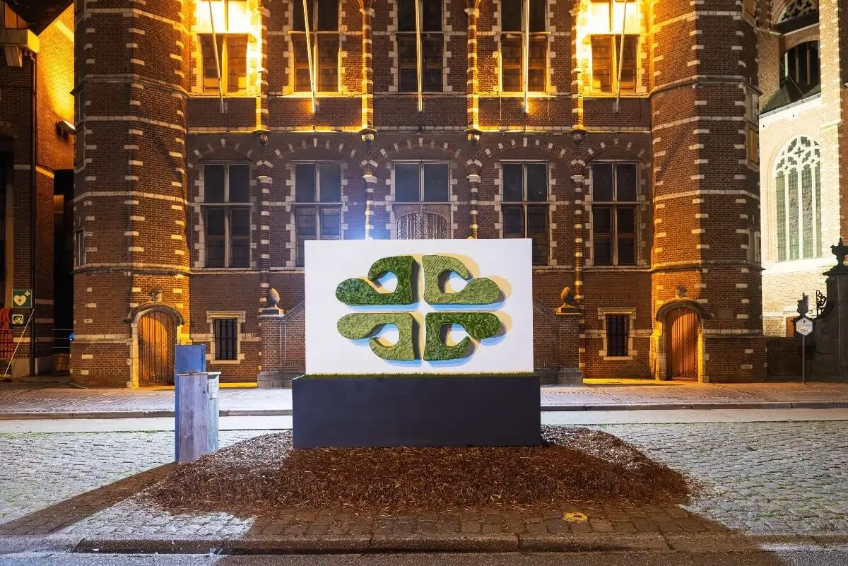 Sculpture végétale monumentale 'Life' recto verso composée de feuilles et haricots verts d'un côté et noirs de l'autre devant une façade historique, design floral architectural, Cindy Gunther