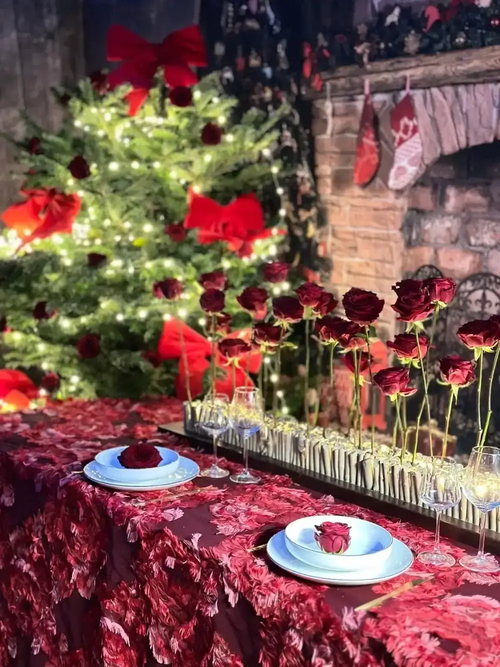 Table de tête-à-tête de Noël avec nappe en tissu haute couture en relief, roses rouges et chemin de table en bois flotté. par Cindy Gunther