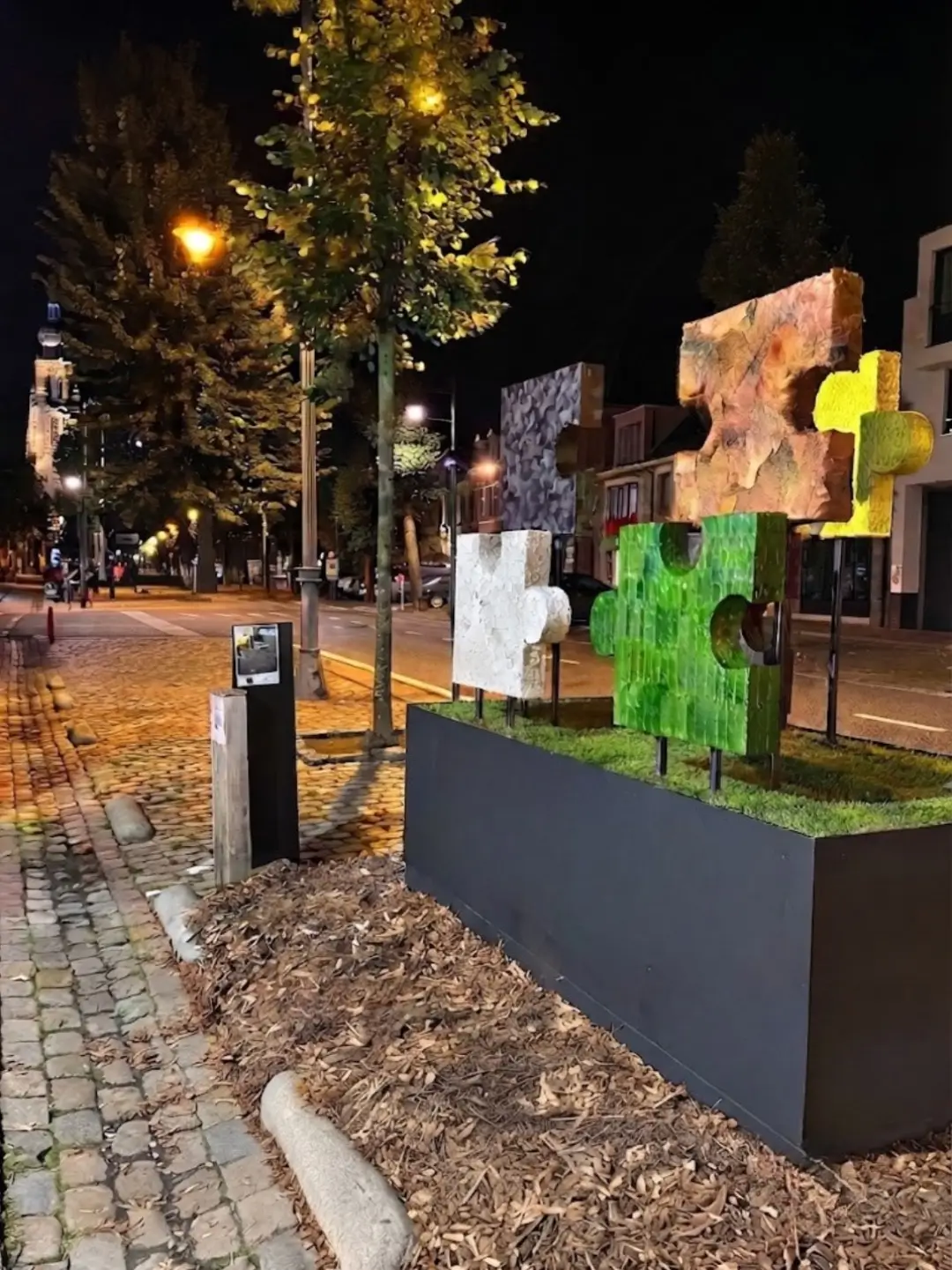 Vue nocturne de l'église illuminée de Hoogstraten en Belgique, mettant en valeur l'œuvre végétale monumentale Puzzle of Life de Cindy Gunther