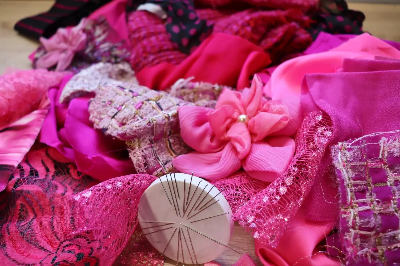 Gros plan sur des fleurs en tissu, des morceaux de textiles et un bracelet magnétique d'aiguilles dans l'atelier de Cindy Gunther