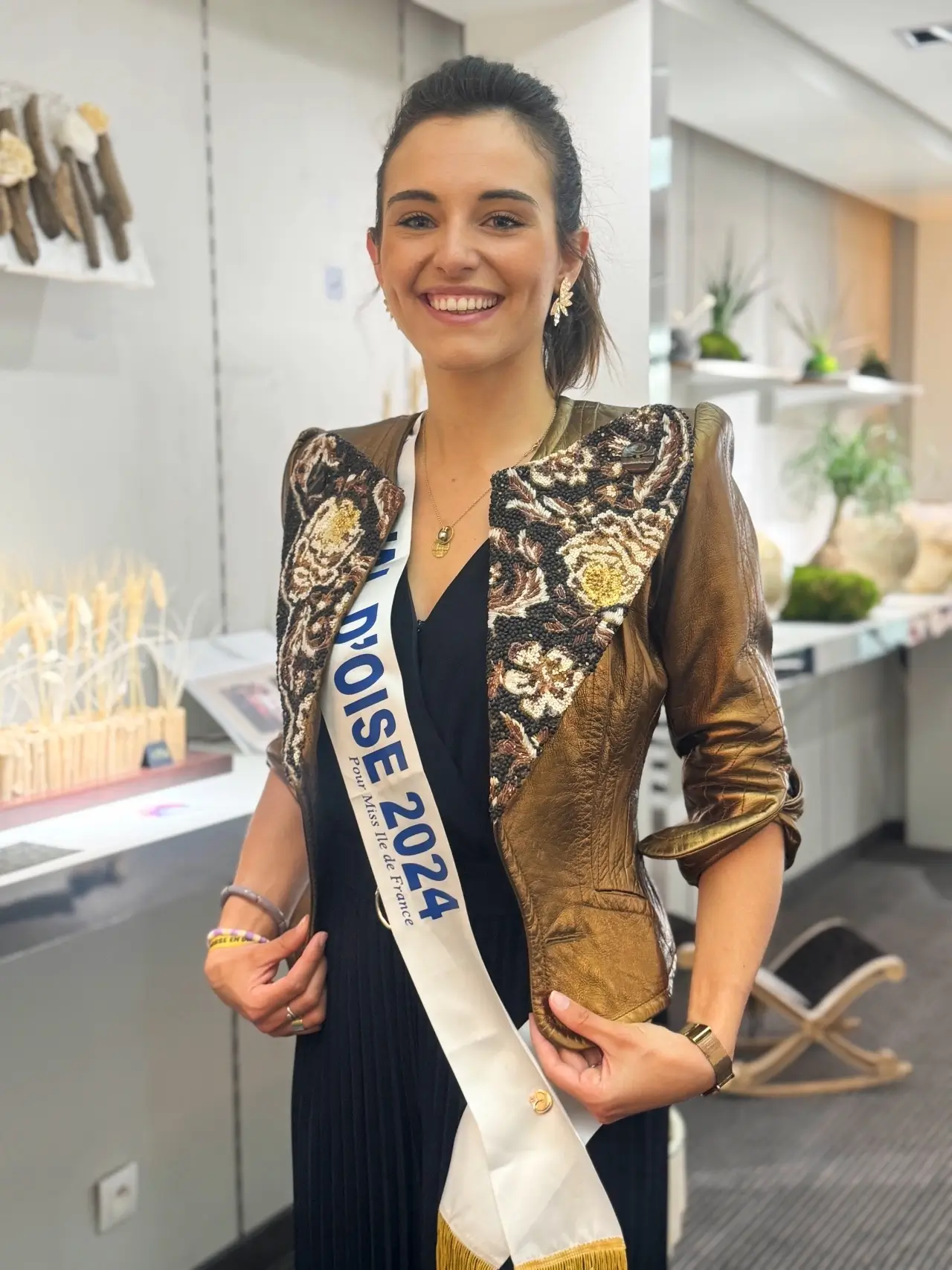 Portrait souriant de Miss Valdoise 2024 portant une veste de créateur à col végétal réalisé par Cindy Gunther et écharpe officielle.